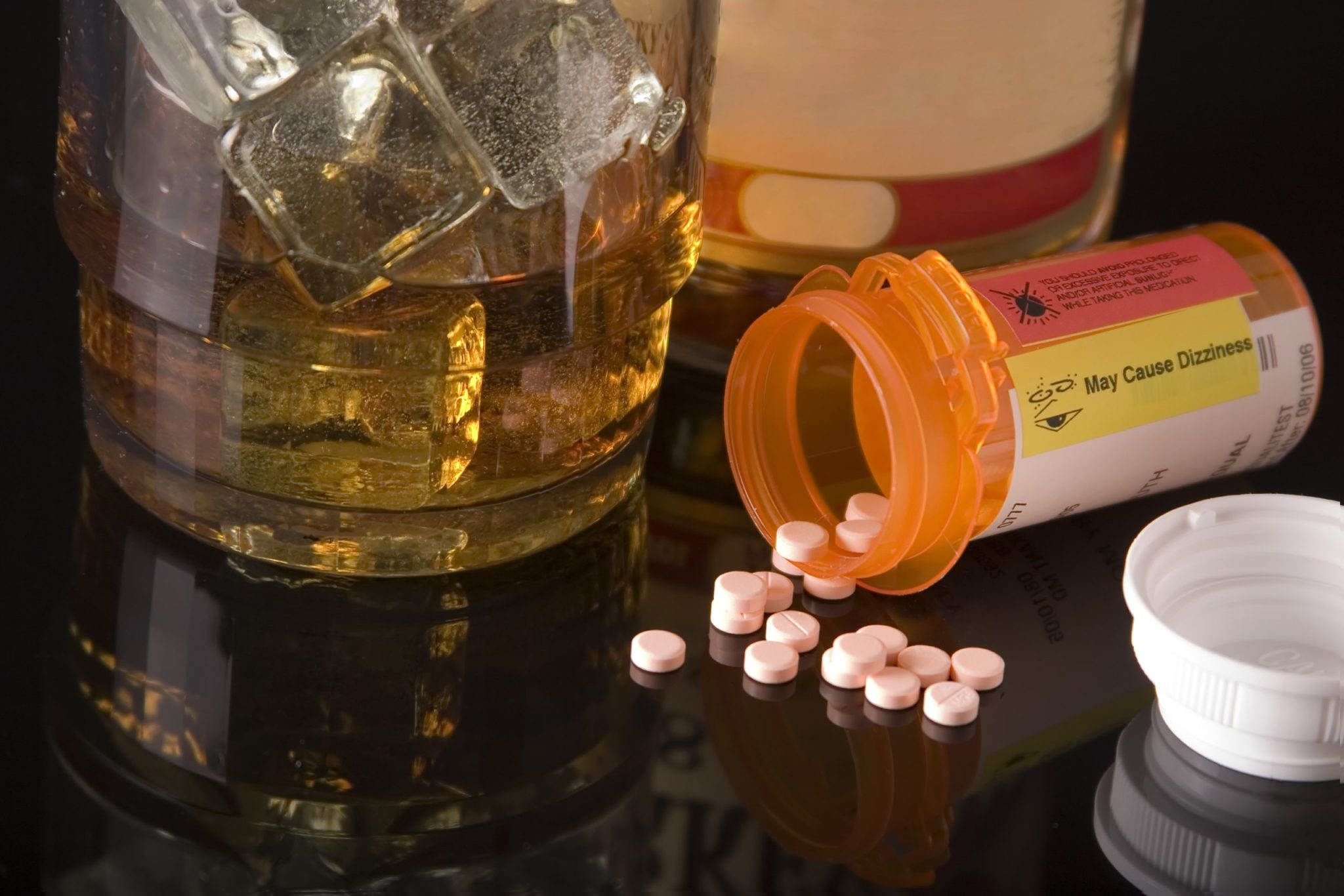 iced alcohol beverage next to tipped klonopin bottle with white pills spilled out