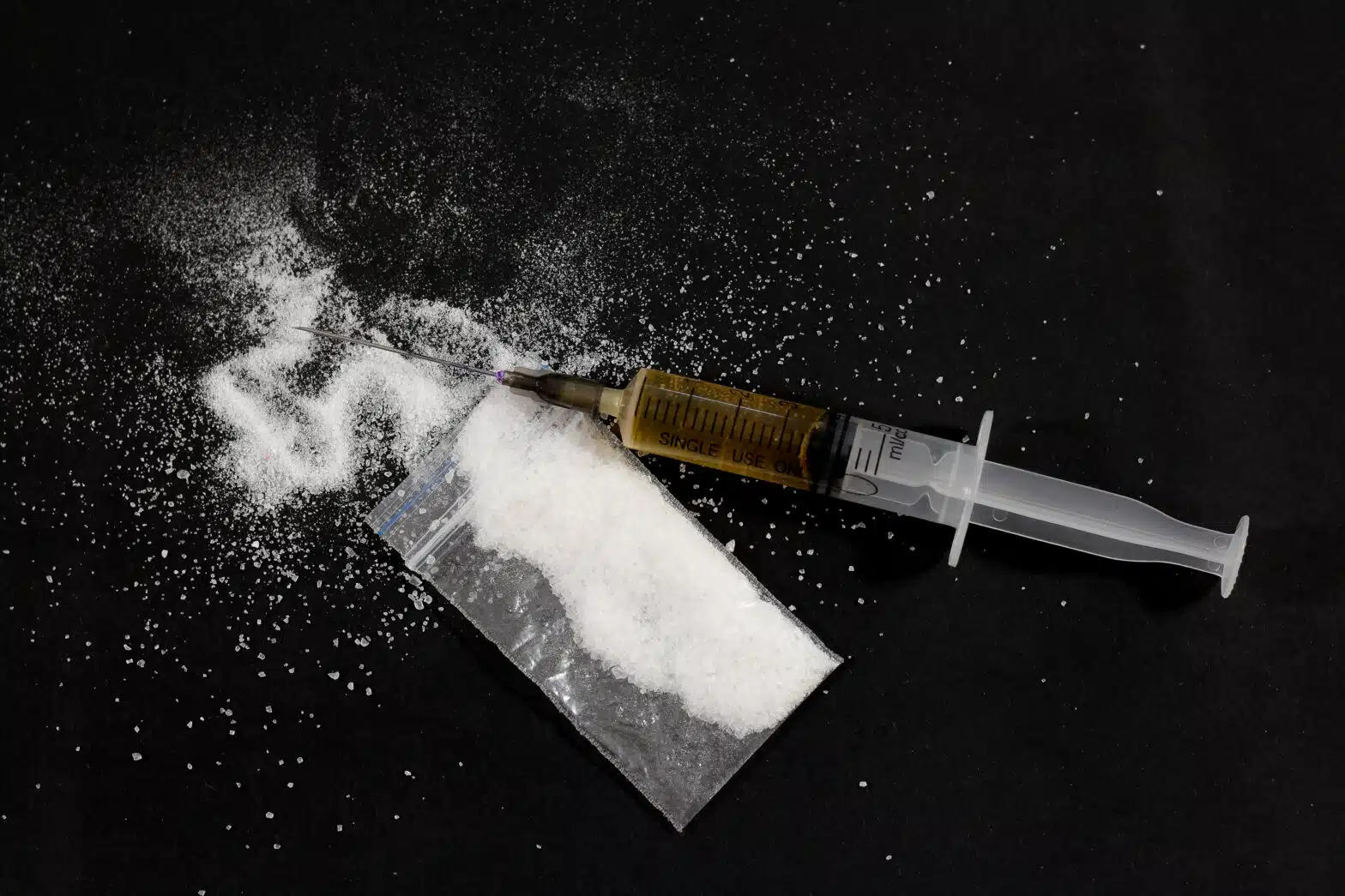 White powder spills out of a plastic bag, a syringe with a brown liquid lays next to it - 7 Signs Your Loved One Is Shooting Up Drugs