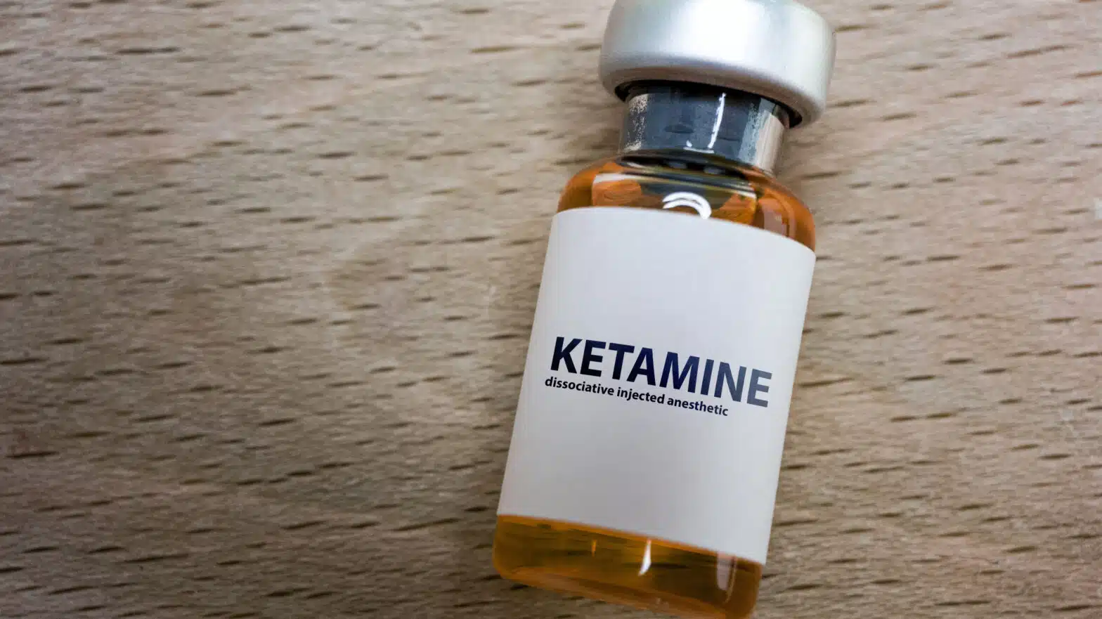 A glass bottle with a label that reads "Ketamine" - Ketamine Addiction & Abuse Signs, Side Effects, & Treatment