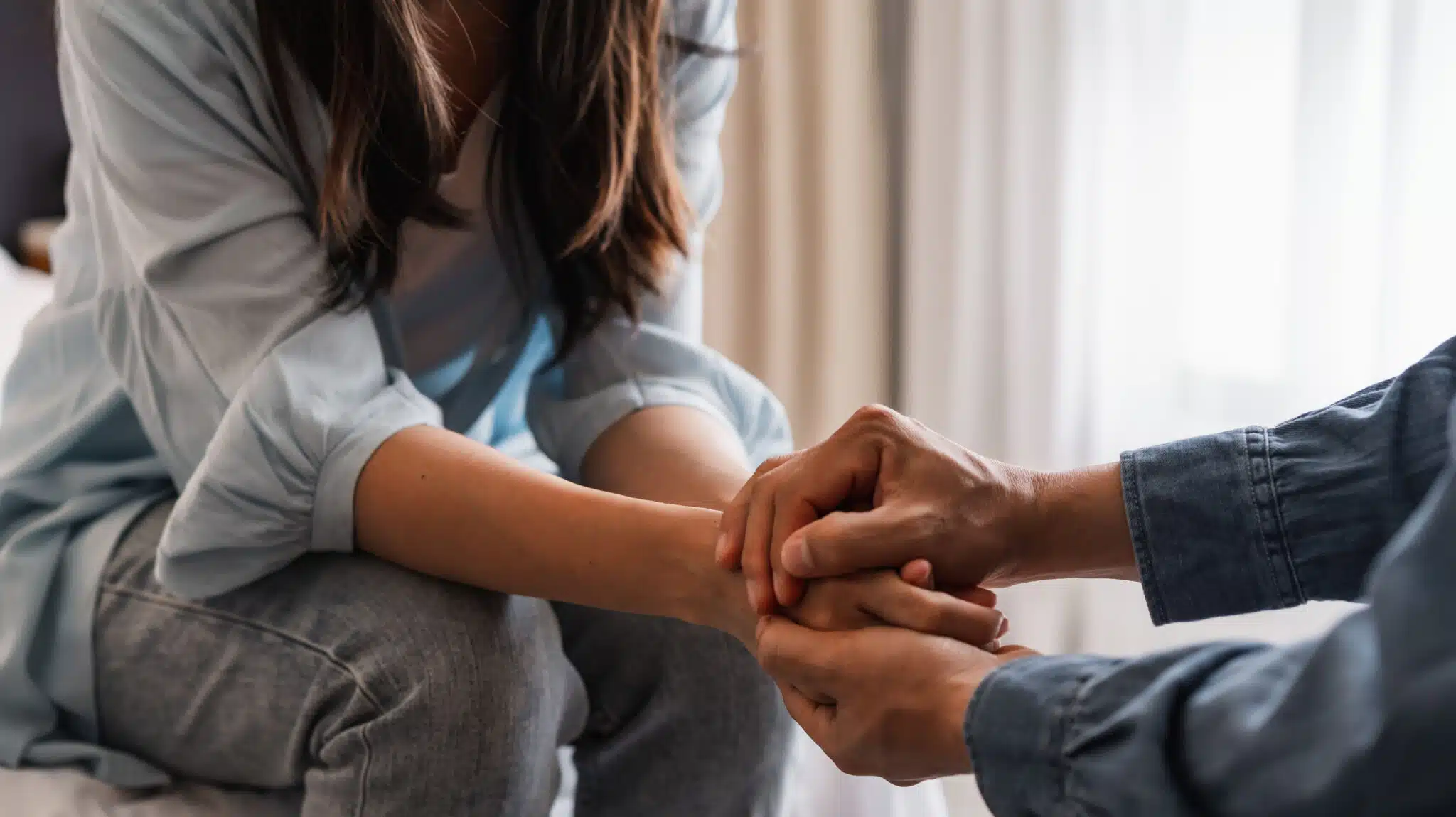 A man holds a woman's hands in a supportive way - Tips For Telling Your Spouse That You Need Addiction Treatment