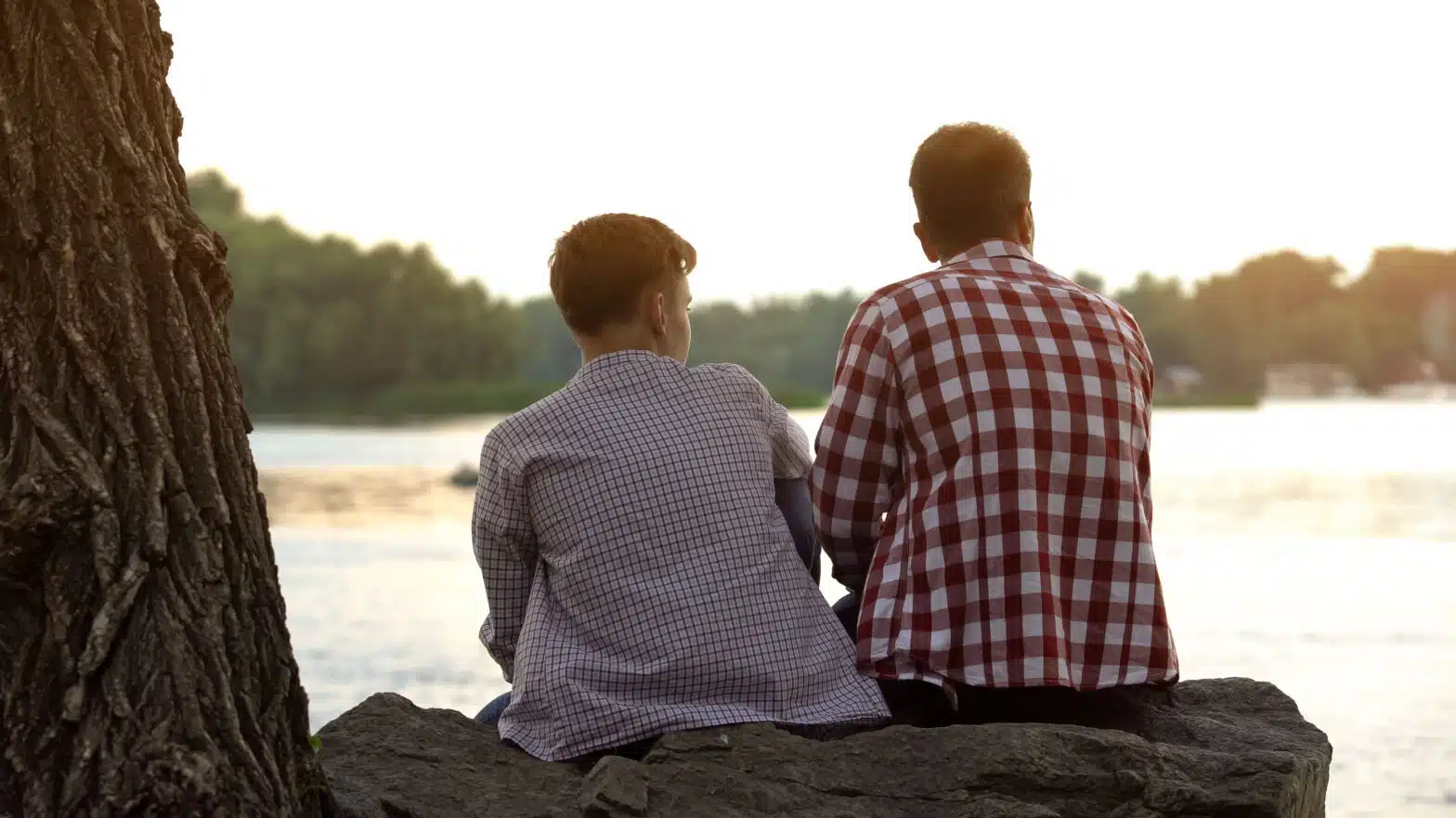 A father and son sit together looking over a lake - Facts For Parents of Children With Addiction