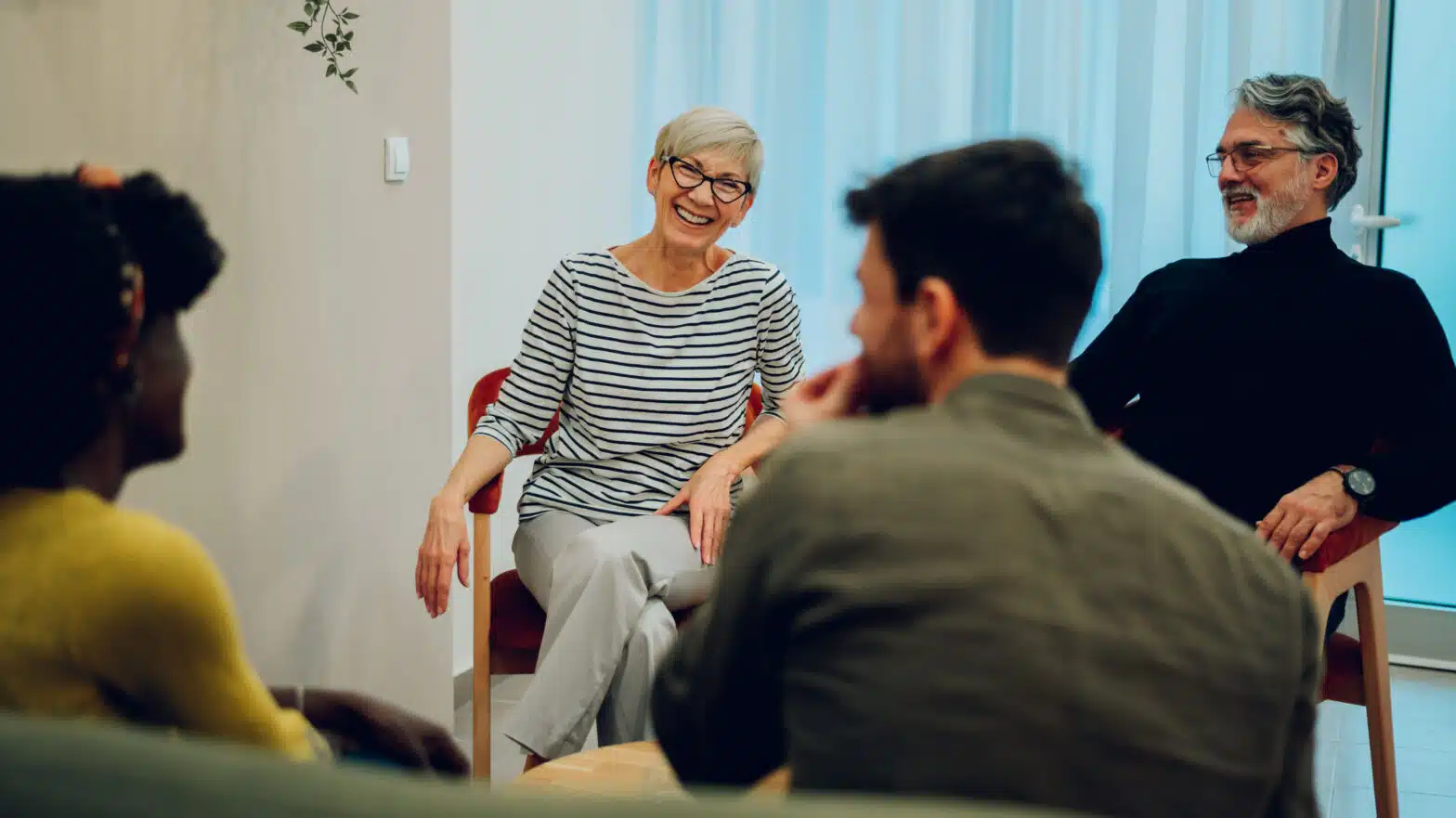 People laugh in a group therapy session - What To Expect In A Typical Day In Drug Rehab