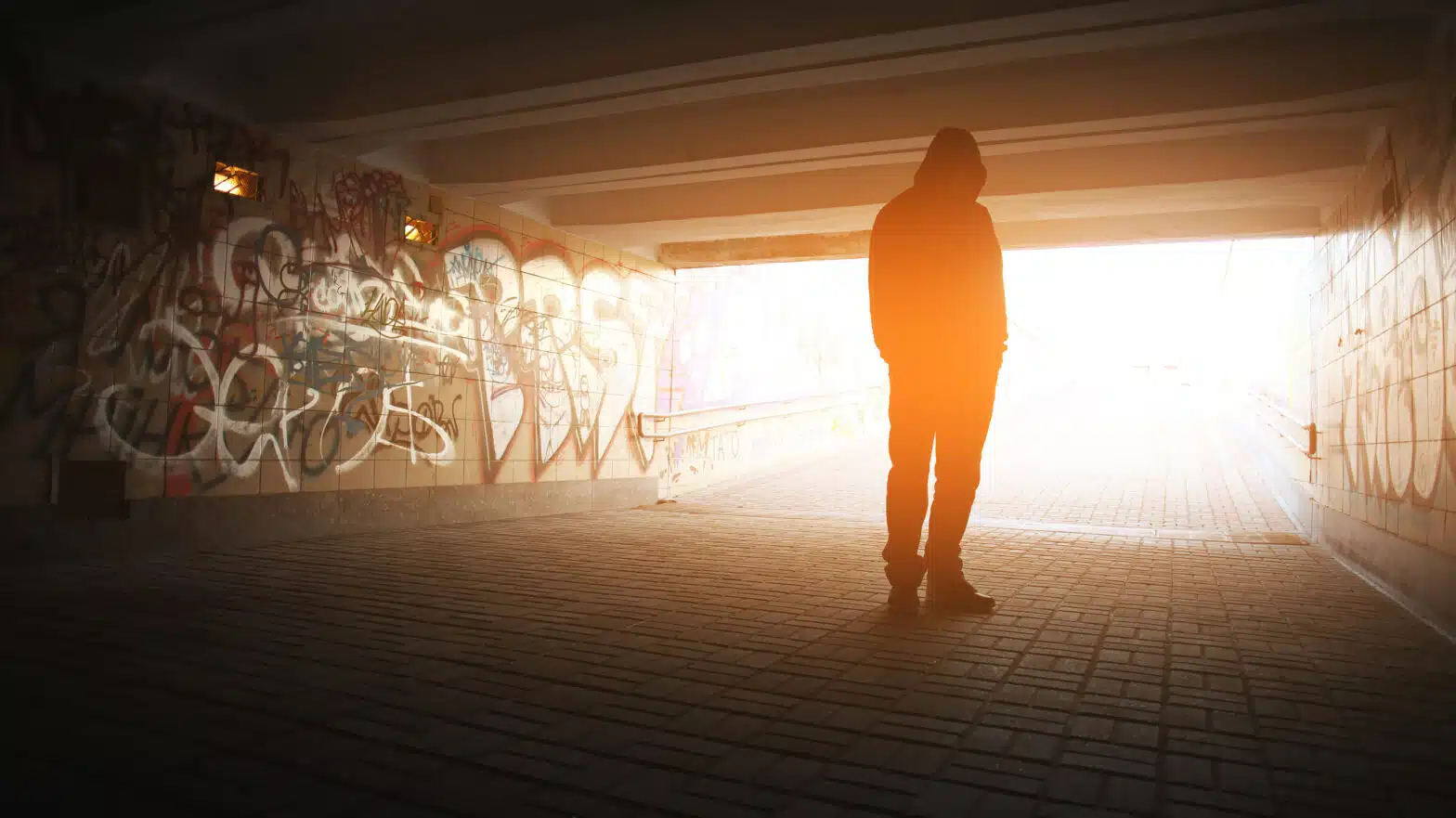 A man stands alone under an overpass - 10 Signs Of Addictive Behavior