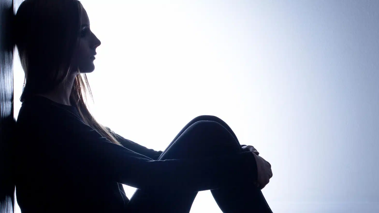 A girl sits in a dark room - Depression (Major Depressive Disorder) Overview & Treatment