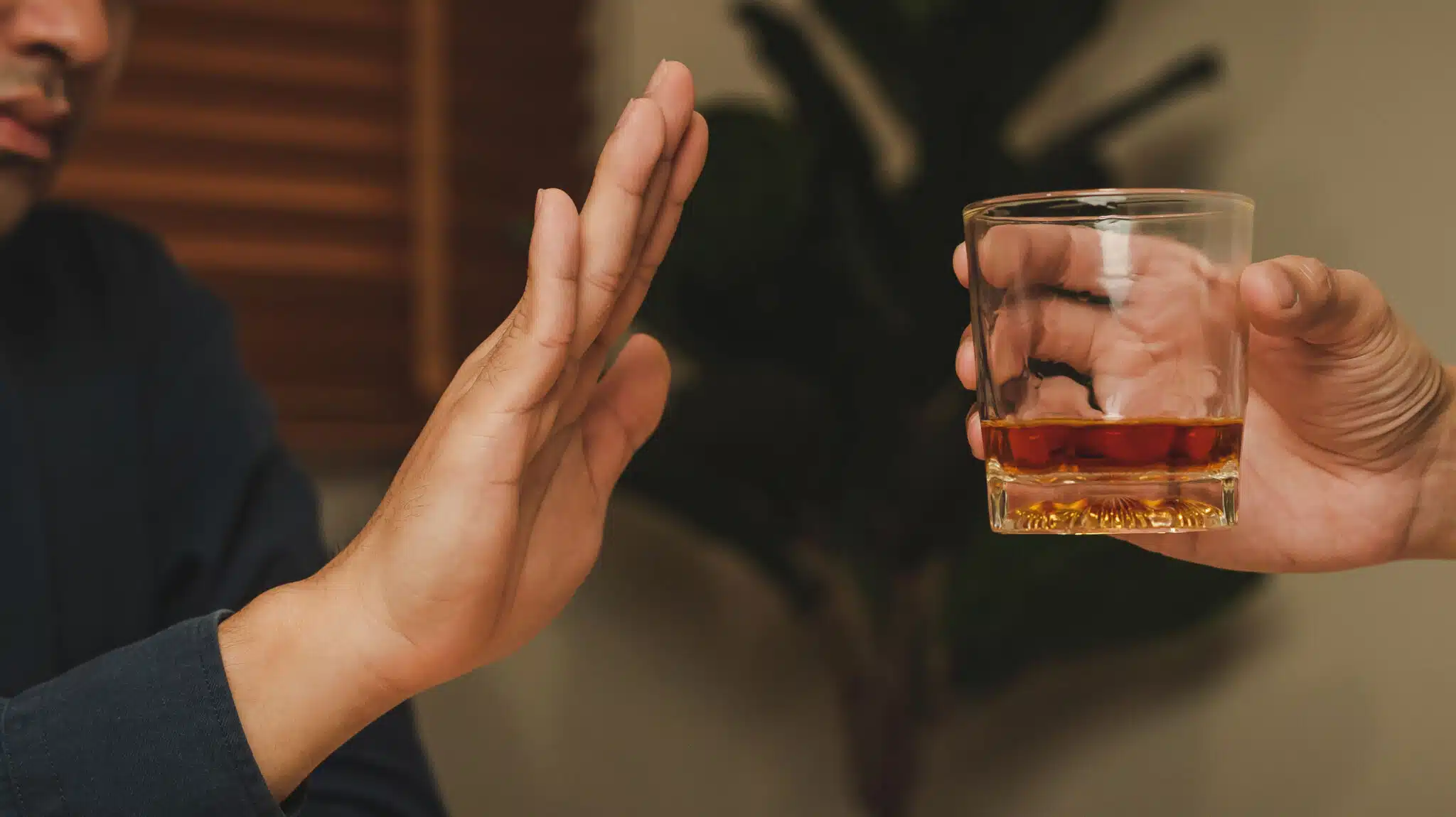 A man holds up his hand rejecting a glass of alcohol - Dealing With Impulse Control In Recovery