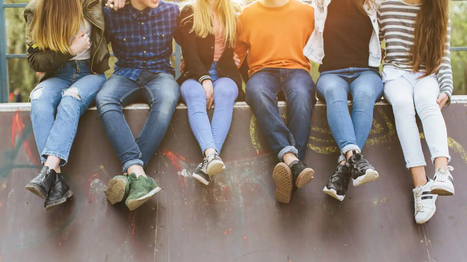 A group of teens sit on a wall dangling their legs - Massachusetts Juvenile Drug Use Statistics