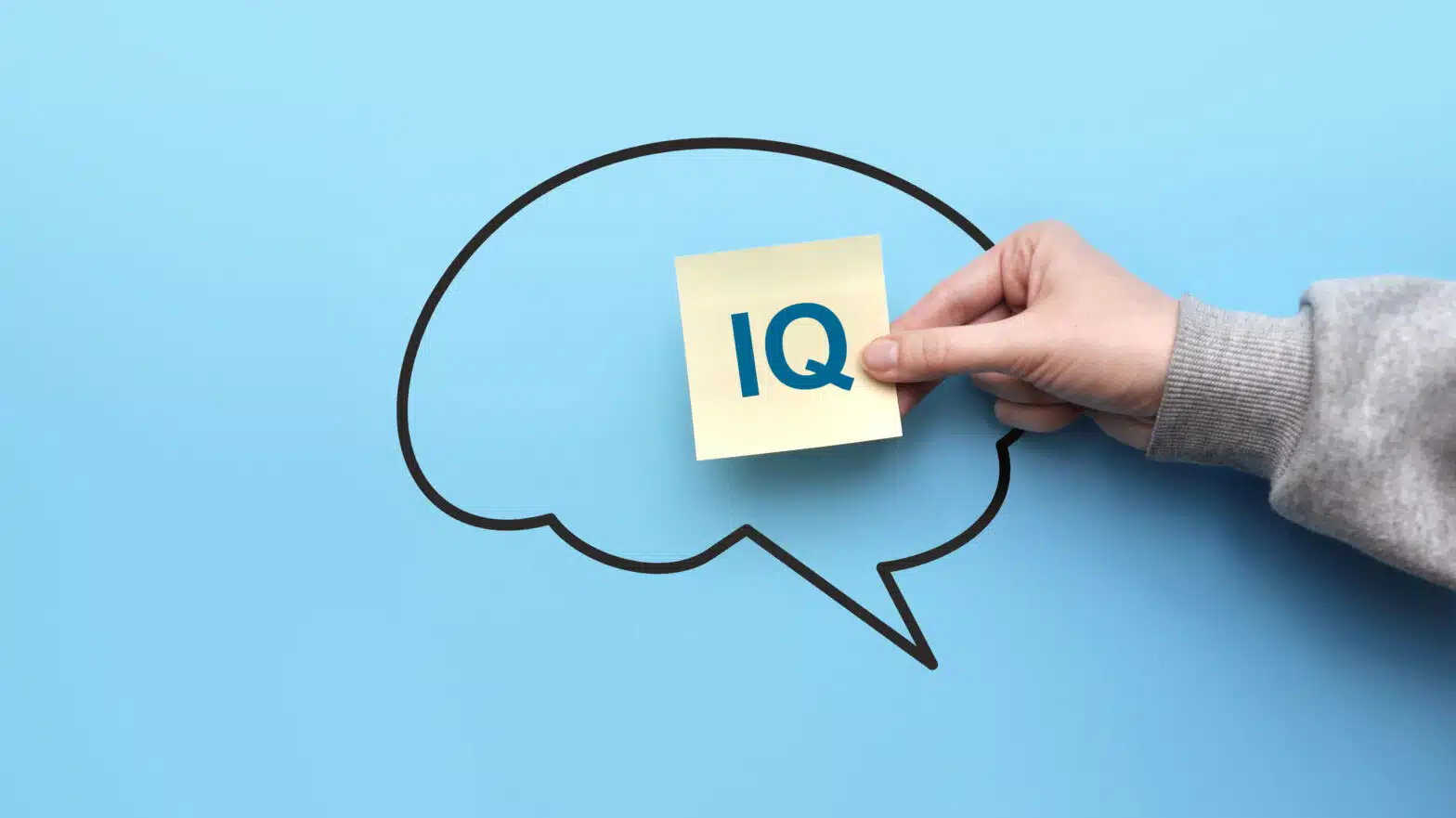 A person holds a sign that reads "IQ" over an outline of a brain - The Correlation Between IQ & Substance Use