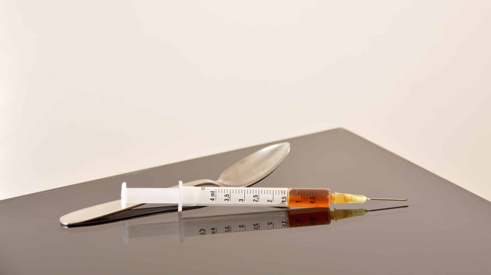 A needle and spoon are on a table - The Thomas Recipe For Heroin Withdrawal